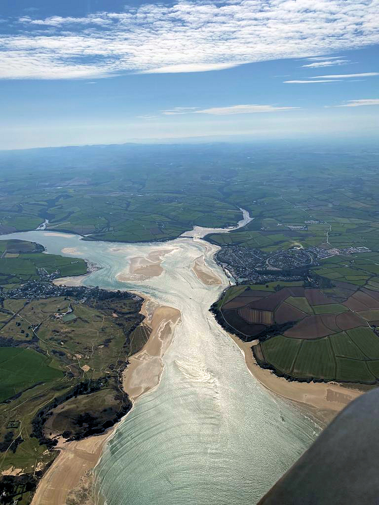 Sunlight on a broad estuary with exposed sandbanks and surrounding countryside