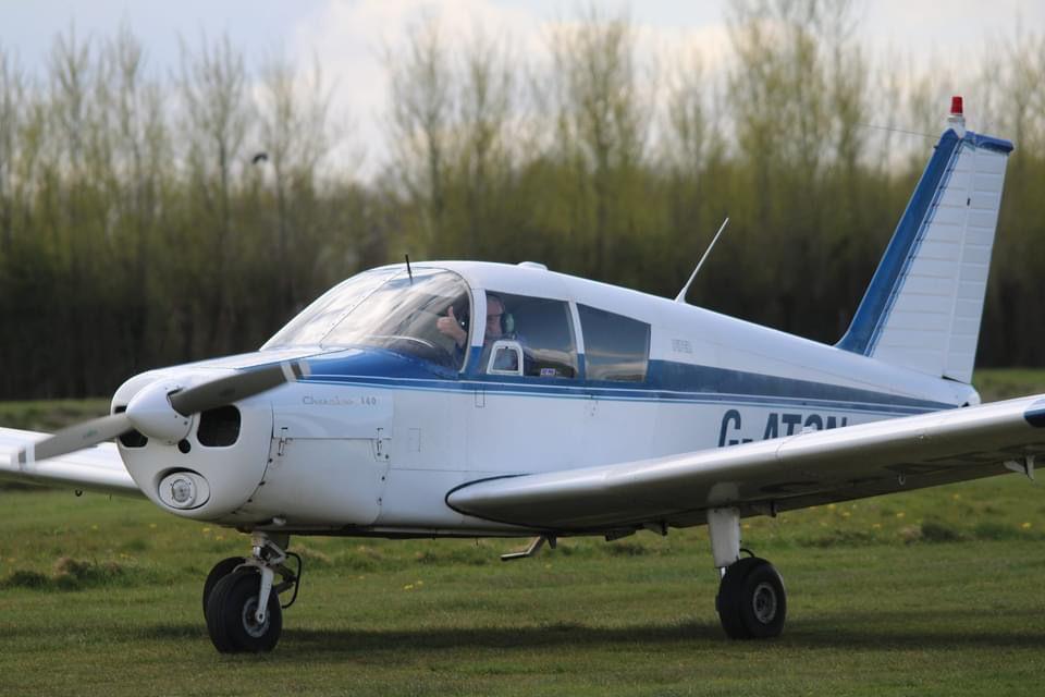 G-ATON, the syndicate’s blue and white Piper PA-28-140 Cherokee, on a grass airfield