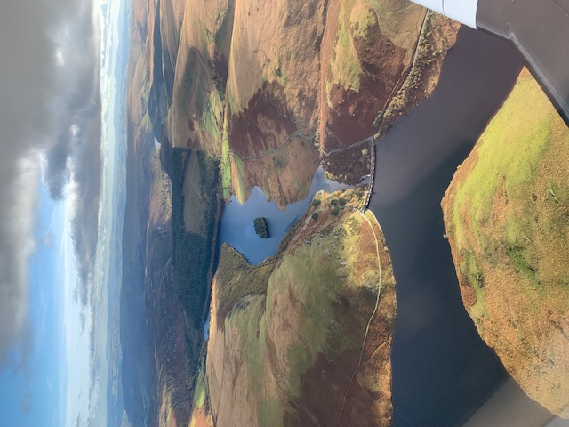 Connected reservoirs and a dam among rolling hills, photographed from the air